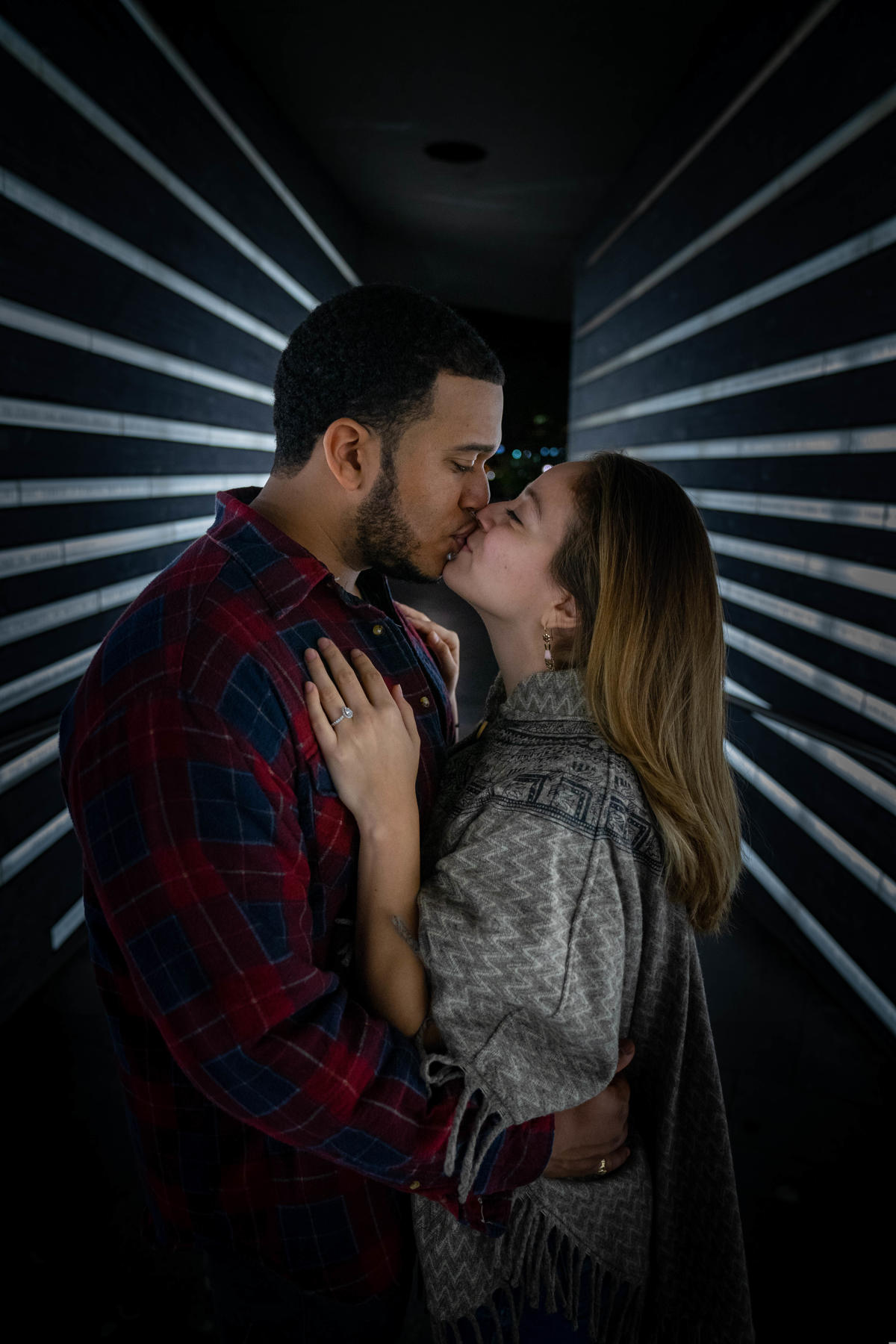 Couple sharing a kiss in a softly lit passageway at night