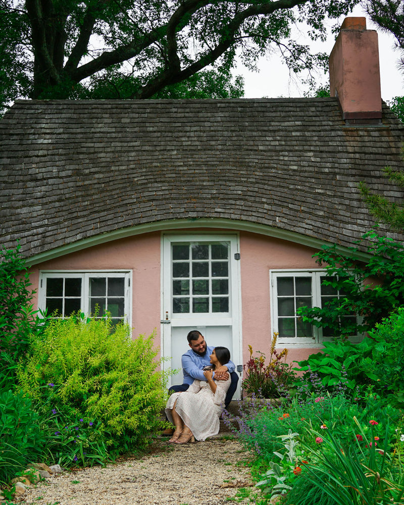 Couple seated in the garden of a pink cottage
