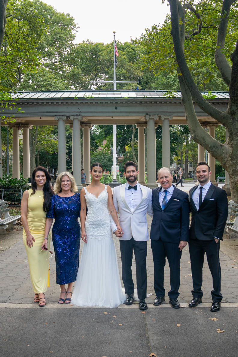 Bride and groom with family in front of the park colonnade