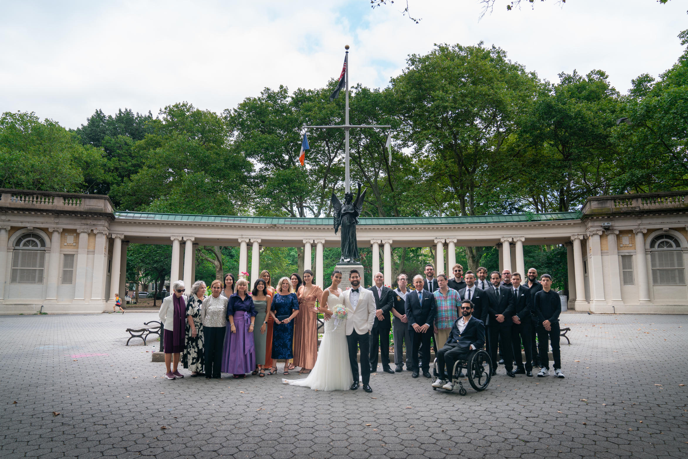 Wide group portrait of the couple with all their guests at the park memorial