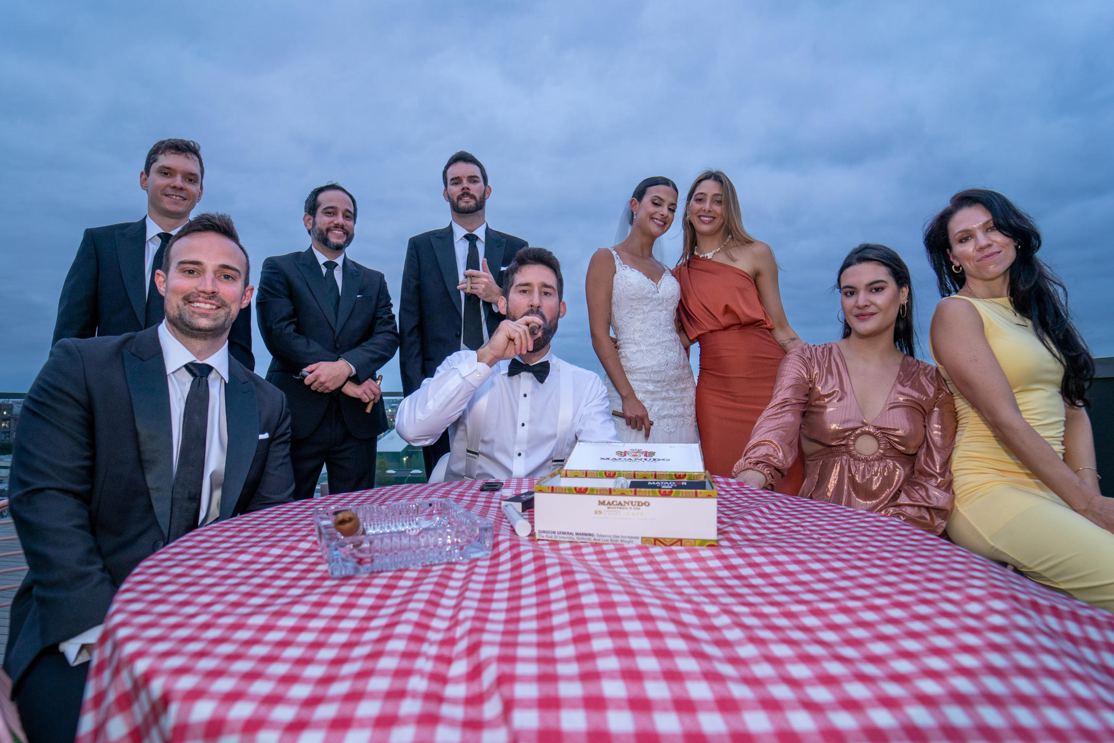 Wedding party gathered around a rooftop table at blue hour